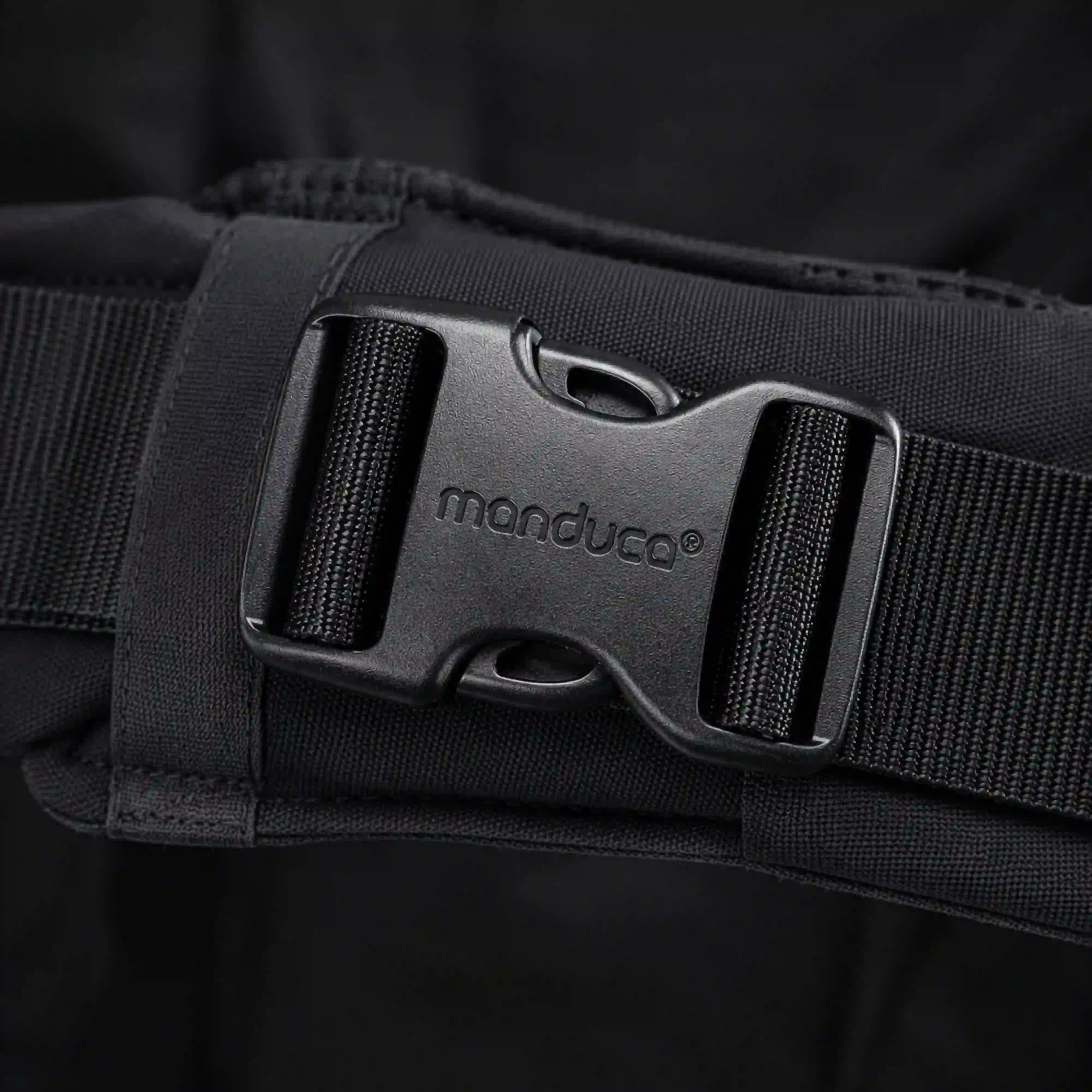Ein Close up des Schriftzuges manduca auf einer Schnalle von der manduca XT Babytrage in monochrome Obsidian