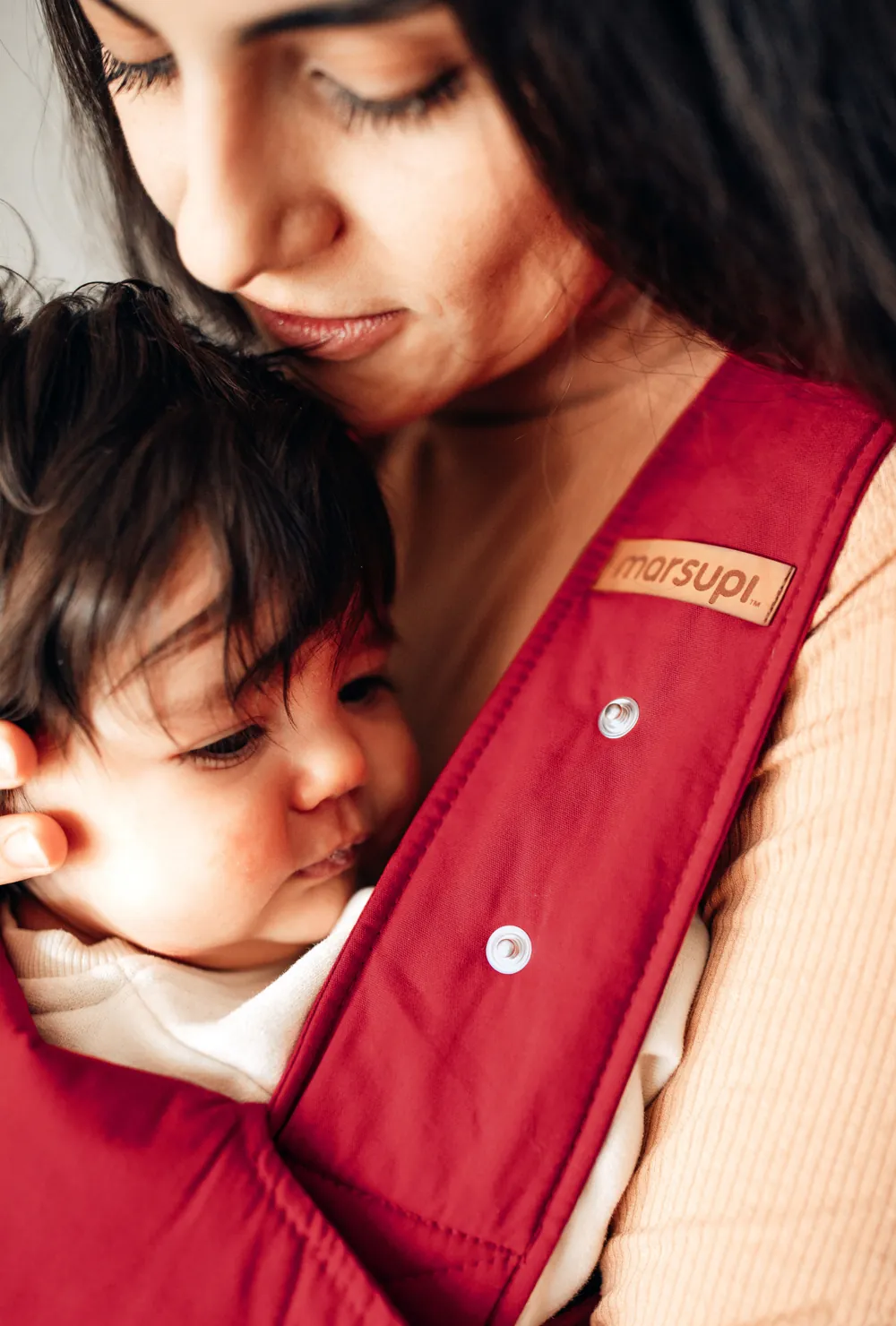 Detailaufnahme: marsupi Label am rubinroten Hüftgurt der Babytrage